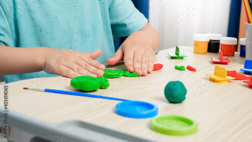 Closeup of little boy forming and shaping colorful plasticine or clay with hands. Special colorful dough for enhancing children motor skills. Child education, creativity and art.
