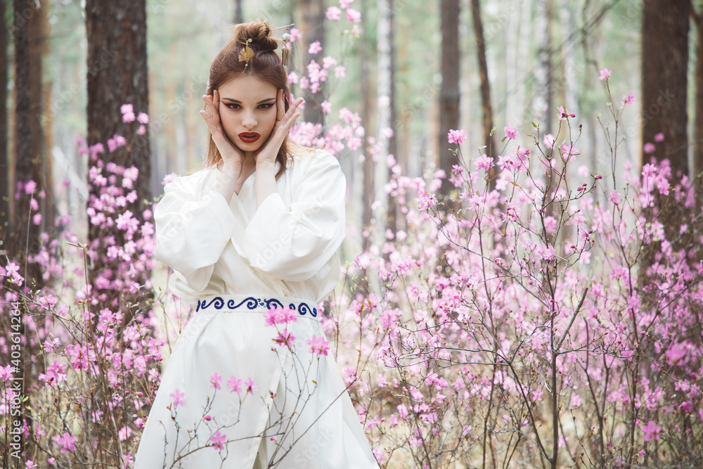 Japanese-style girl in a flowering forest among pink flowers in spring Japanese-style girl in a flowering forest among pink flowers in spring