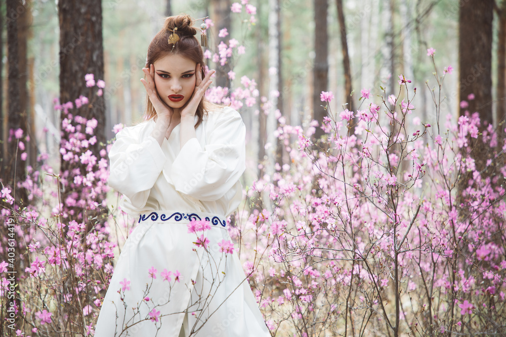 Japanese-style girl in a flowering forest among pink flowers in spring Japanese-style girl in a flowering forest among pink flowers in spring