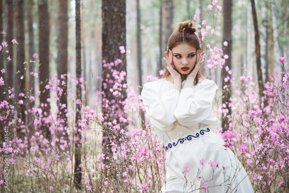 Japanese-style girl in a flowering forest among pink flowers in spring Japanese-style girl in a flowering forest among pink flowers in spring