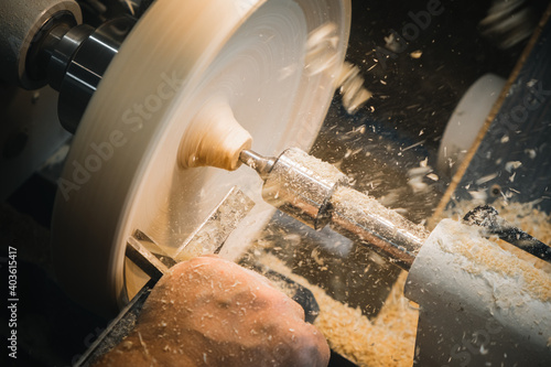 Fototapeta a man in a working apron works on a wood turning lathe