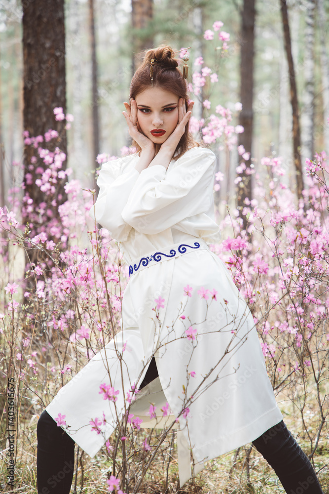 Japanese-style girl in a flowering forest among pink flowers in spring Japanese-style girl in a flowering forest among pink flowers in spring