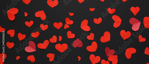 Many little red hearts on a black background. Background for decor.Banner