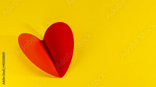 Beautiful folded red heart on a yellow background. Close-up. Minimalism. Valentine s day