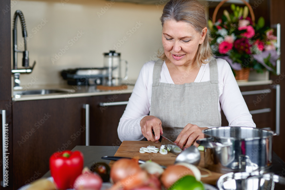 Senior woman in kitchen preparing food.