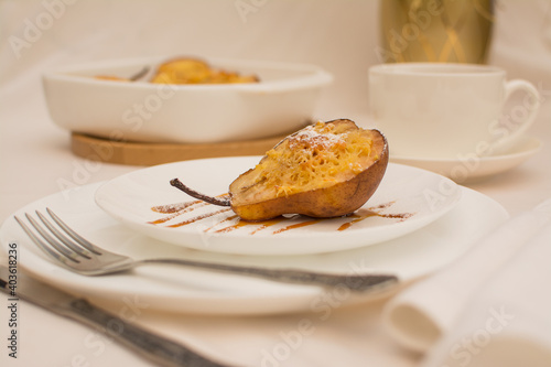 Baked pears with nuts and cheese on a white ceramic plate with caramel.