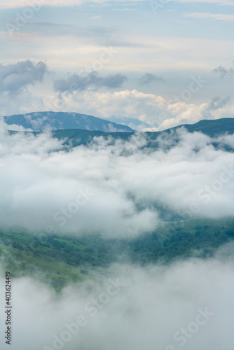 White fluffy clouds over the Scottish mountains with distant views of Meall Buidhe and Meall Clachach from above Loch Tay in the Scottish Highlands, UK.