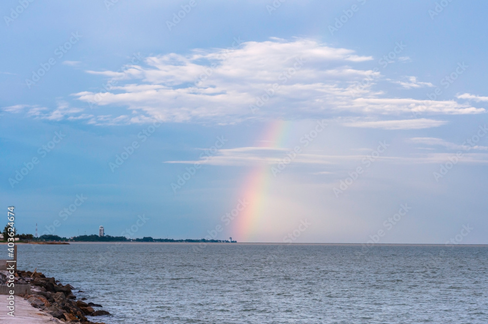 Rainbow on the sea with blue sky after raining.