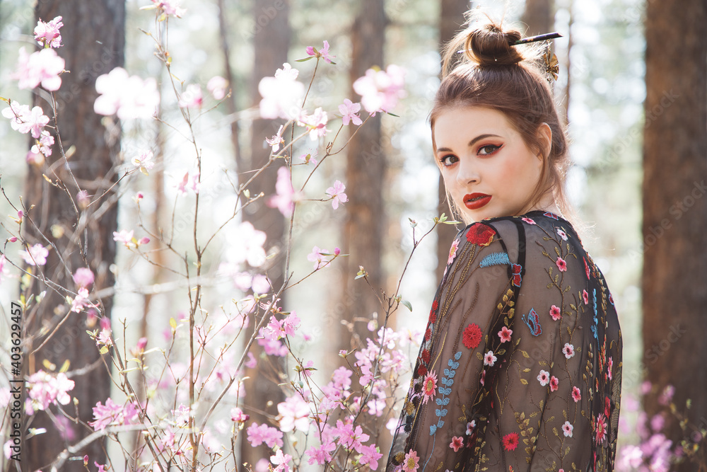 Japanese-style girl in a flowering forest among pink flowers in spring Japanese-style girl in a flowering forest among pink flowers in spring