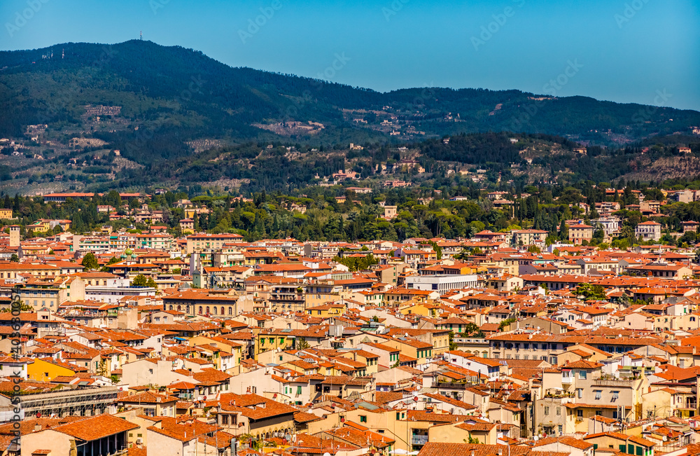 Beautiful panoramic aerial view of the historic centre of Florence surrounded by the Florentine hills, planted with olive groves and vineyards, and dotted with villas on a sunny day with a blue sky.