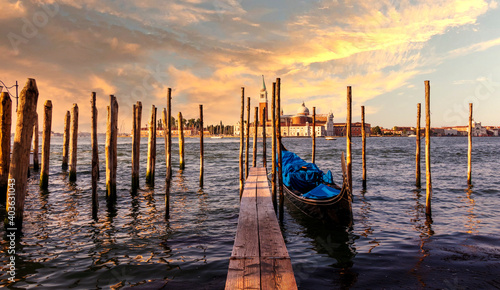 Fototapeta Naklejka Na Ścianę i Meble -  Beautiful seascape of Venice while sunset with gondola boat near by the pier in front of the basilica historical building by the ocean. 