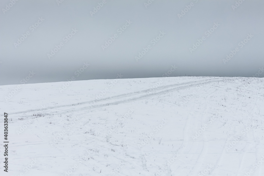 Snowy hill on a field with cloudy sky
