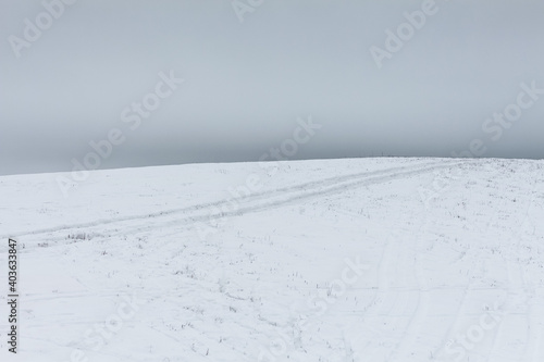 Snowy hill on a field with cloudy sky