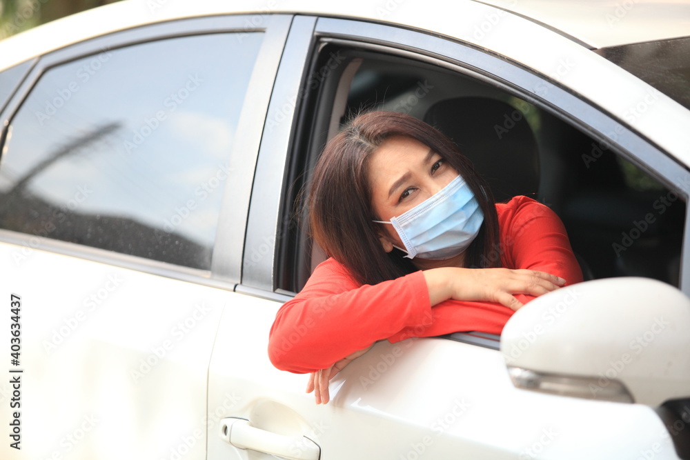 Young woman with medical protective mask on her face is driving a car, she looks into camera and View from outside , Protect yourself. Young woman with medical protective mask on her face is driving a car, she looks into camera and View from outside , Protect yourself.