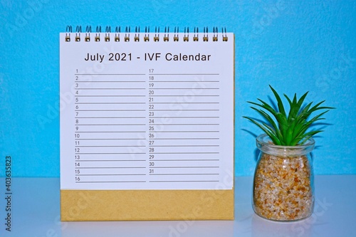 July 2021 IVF calendar with blue background and potted plant