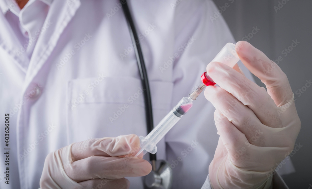 Coronavirus vaccine and development and creation COVID-19 vaccine concept.Doctor hand in gloves hold medical vaccine bottles dose and syringe ready to treat the patient. Coronavirus vaccine and development and creation COVID-19 vaccine concept.Doctor hand in gloves hold medical vaccine bottles dose and syringe ready to treat the patient.