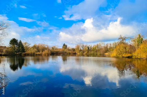 Panoramic view of a lake, called Altwasser in German.
Peaceful landscape with trees on the shore and cumulus clouds in the blue sky. Neuburg am Rhein, Rhineland-Palatinate, Germany