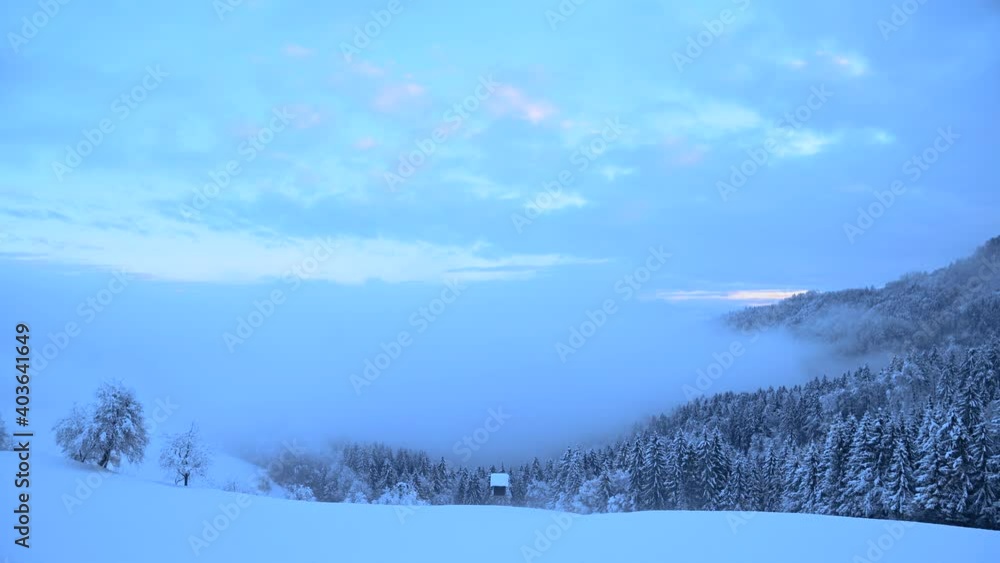Time lapse view of inversion clouds moving in Alpine valley in winter season. Beautiful landscape covered with snow in Slovenia. Fog moving over spruce forest. Static shot, wide angle Time lapse view of inversion clouds moving in Alpine valley in winter season. Beautiful landscape covered with snow in Slovenia. Fog moving over spruce forest. Static shot, wide angle