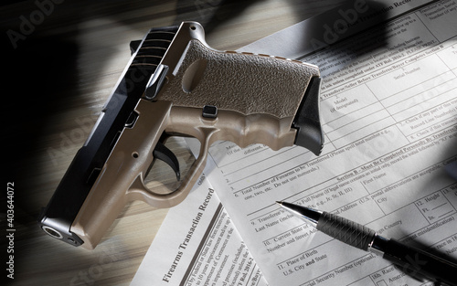 Polymer pistol and pen resting on the publiic domain form required to purchase a gun photo