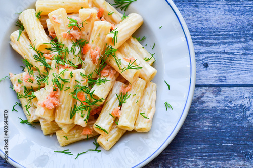  Italian home made macaroni pasta with smoked salmon , creamy sauce and fresh dill on wooden background