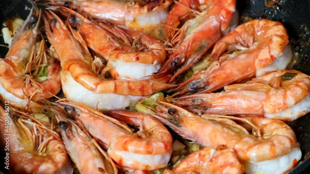 Black Tiger Shrimps Roasted with herbs. Grilled fresh shrimps on gas stove being fried in pan with butter or oil. Frying raw prawns. Concept of cooking shrimps with spices. Close-up closeup macro 4K Black Tiger Shrimps Roasted with herbs. Grilled fresh shrimps on gas stove being fried in pan with butter or oil. Frying raw prawns. Concept of cooking shrimps with spices. Close-up closeup macro 4K
