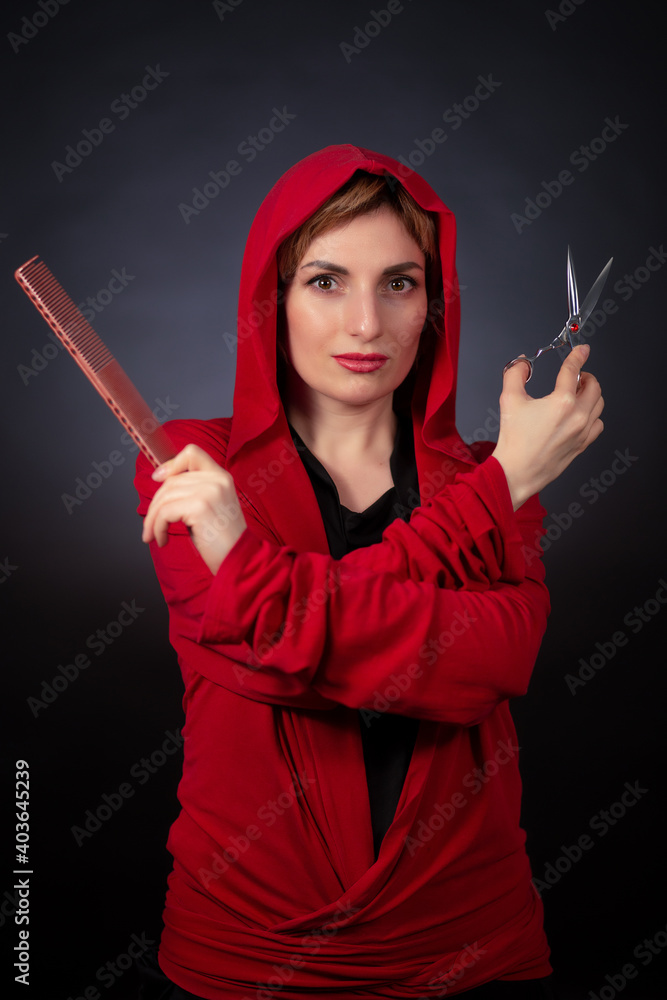 The hairdresser in red witn scissors and a comb on a dark background