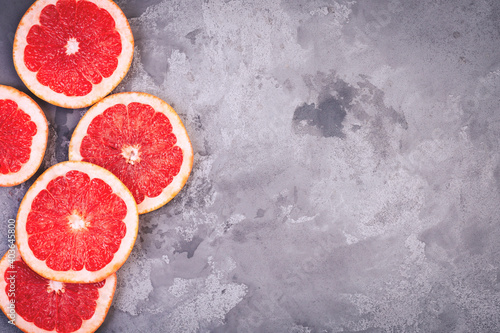 Sliced ​​grapefruit rings on gray concrete grunge background. Copyspace.