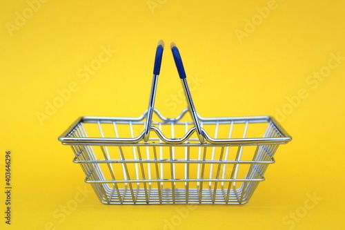 Empty shopping basket stands on yellow background