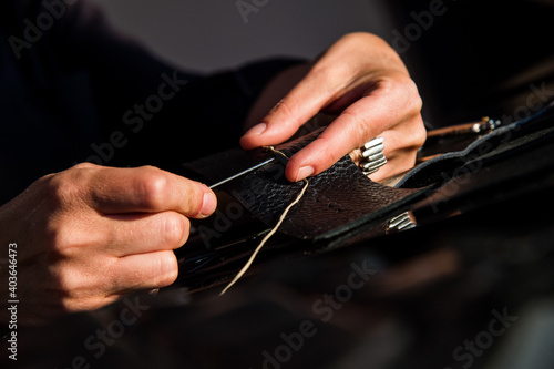 A leather craftsman works with leather. Sews leather goods. Use needle and thread for sewing. Making things handmade..