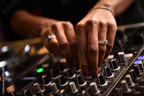 Audio mixer console and professional sound mixing. A female black hand is adjusting audio mixer with buttons and sliders. Mixer console for musician DJ and sound engineers.