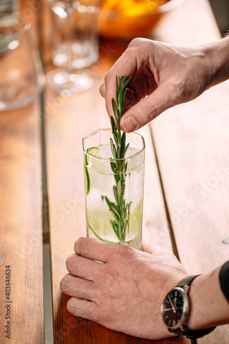 Closeup on man making fresh gin tonic cocktail with lime slices