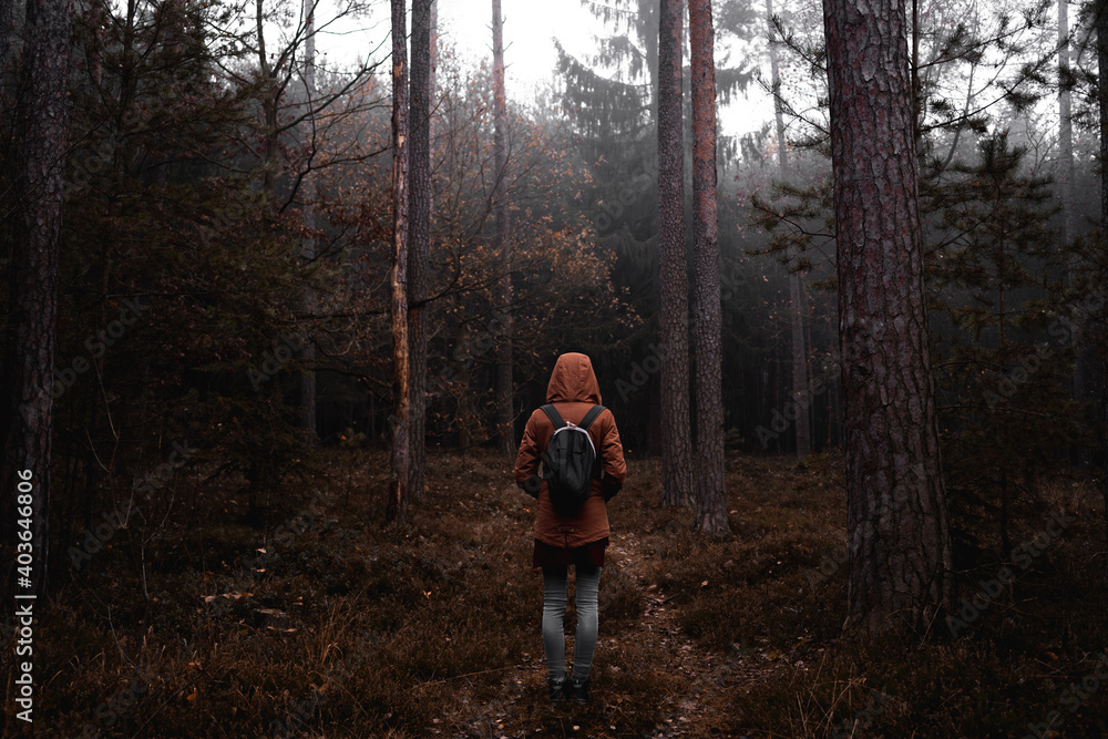Girl with backpack from behind in the woods