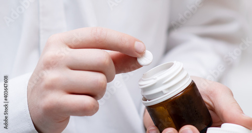 close-up image a tablet with a medicine is placed in a jar by the hands of a child