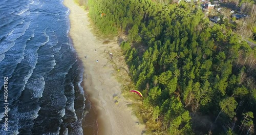 Aerial view of parasailers and tourists on beach with calm waves reaching the shore, sunny day. 4k. photo