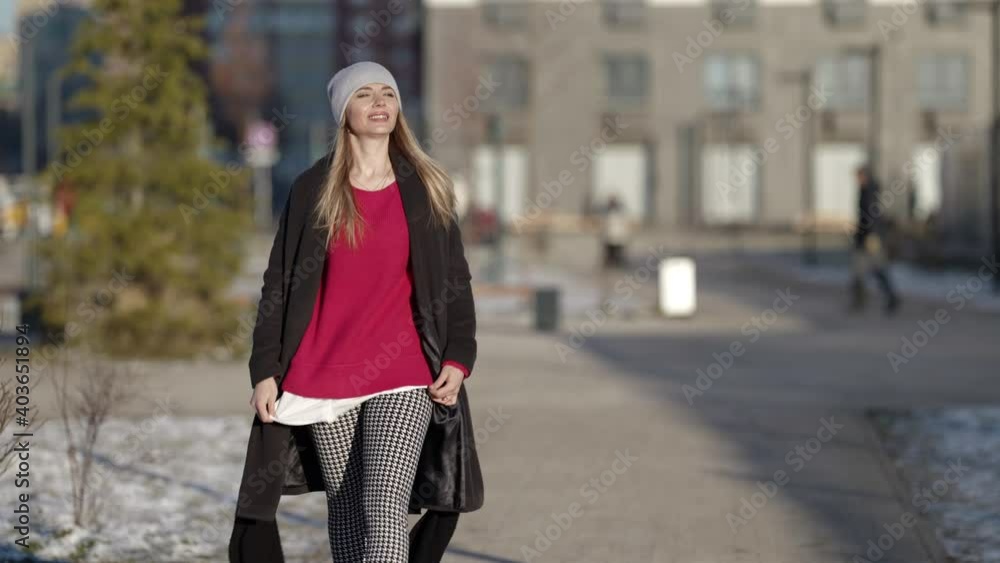 A fashionable young happy smiling woman in a coat and hat walks and poses on the street of the city. Autumn, winter fashion. A fashionable young happy smiling woman in a coat and hat walks and poses on the street of the city. Autumn, winter fashion.