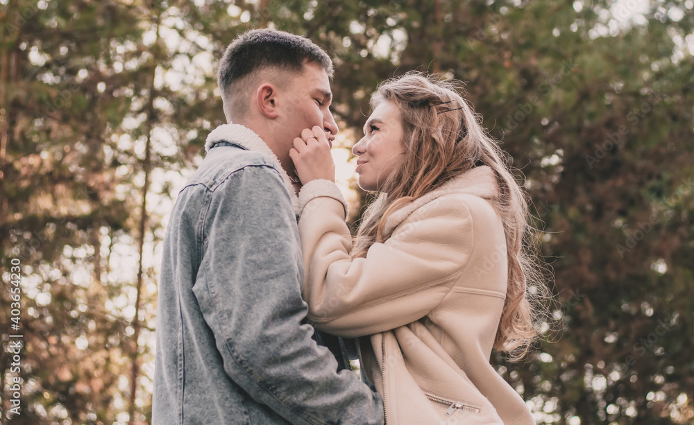 A girl holds a guy by the face with her hands and smiles at him while walking in a pine forest A girl holds a guy by the face with her hands and smiles at him while walking in a pine forest