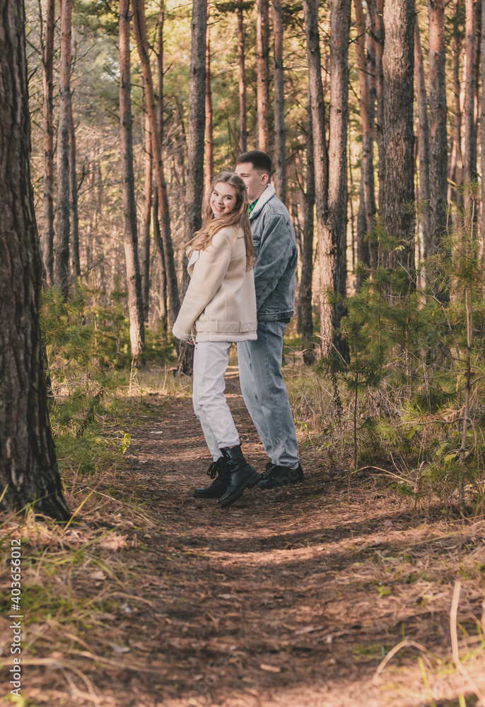 a couple walks in a pine forest in the tropics a guy holds a girl's hand while she looks into the frame a couple walks in a pine forest in the tropics a guy holds a girl's hand while she looks into the frame