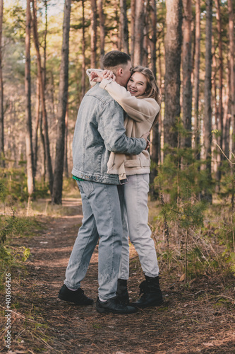  the guy hugs the girl tightly and kisses her on the cheek while in the pine forest © Катя Данилюк
