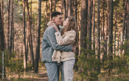  the guy hugs the girl tightly and kisses her while in the pine forest