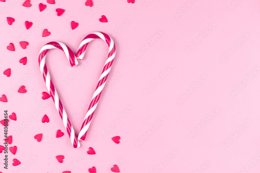 Red or pink confectionery confetti in the shape of hearts and candy canes on a pink background copy space