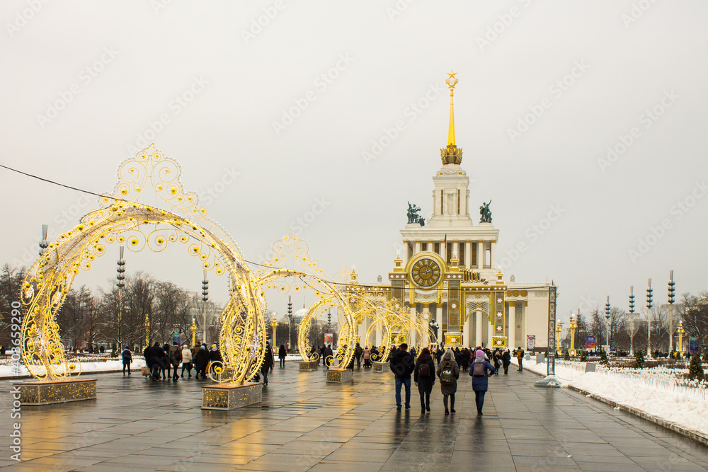 panoramic view of vdnkh Park with historical palaces pavilions and New Year decorations and people walking on a cloudy winter day and space for copying in Moscow Russia