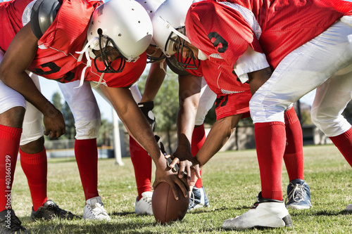 Portrait of Football Players in Huddle Holding Football