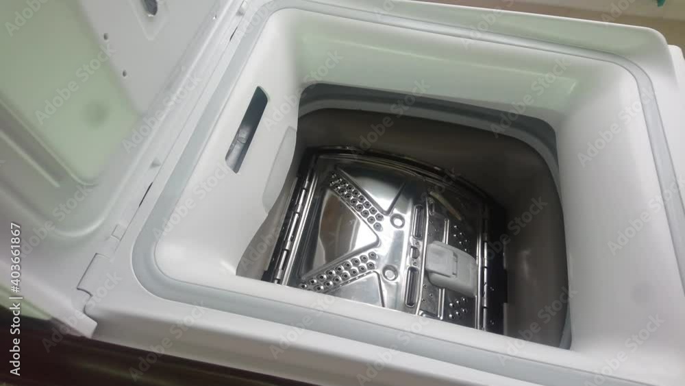 Woman loads dirty clothes into a vertical washing machine Woman loads dirty clothes into a vertical washing machine