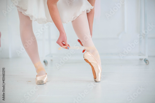 ballerina wears and ties ballet flats before ballet dance show, professional costume, the beauty of classical ballet.