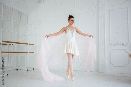 young ballerina in a white dress dancing in a bright studio