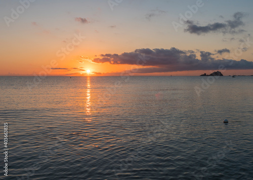 Sunrise with the red orange sun raising up from the sea with dark clouds at beach Spiaggia di Santa Maria Navarrese  Sardinia  Italy