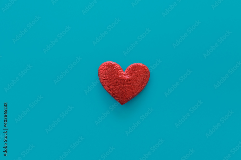 Red heart on blue background. Central composition. Love and passion minimal concept Red heart on blue background. Central composition. Love and passion minimal concept