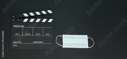 Black Clapper board or movie slate with face mask. it use in video production,movies and cinema industry on black background.	
