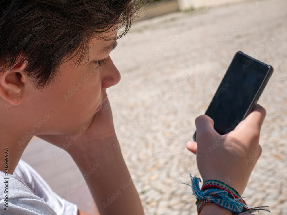 Photo of bored boy using his smartphone
