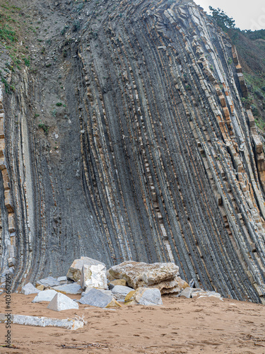 Fotografie rock formations with vertical strata or flysch in a beach in the Basque country